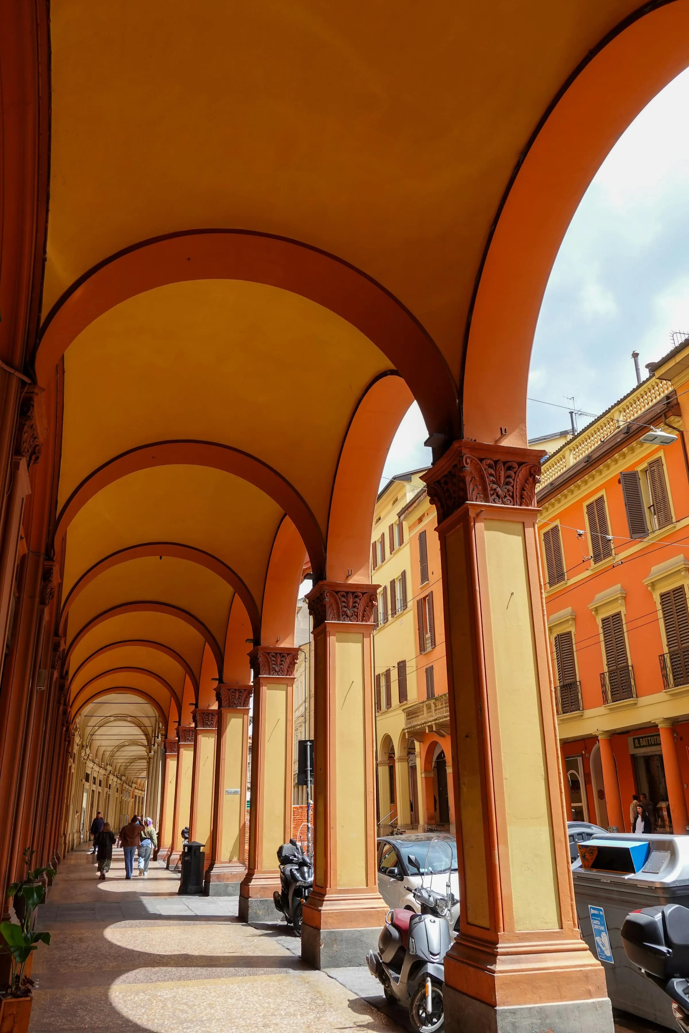 Portico bolognese ocra e arancione, con le persone che ci camminano sotto