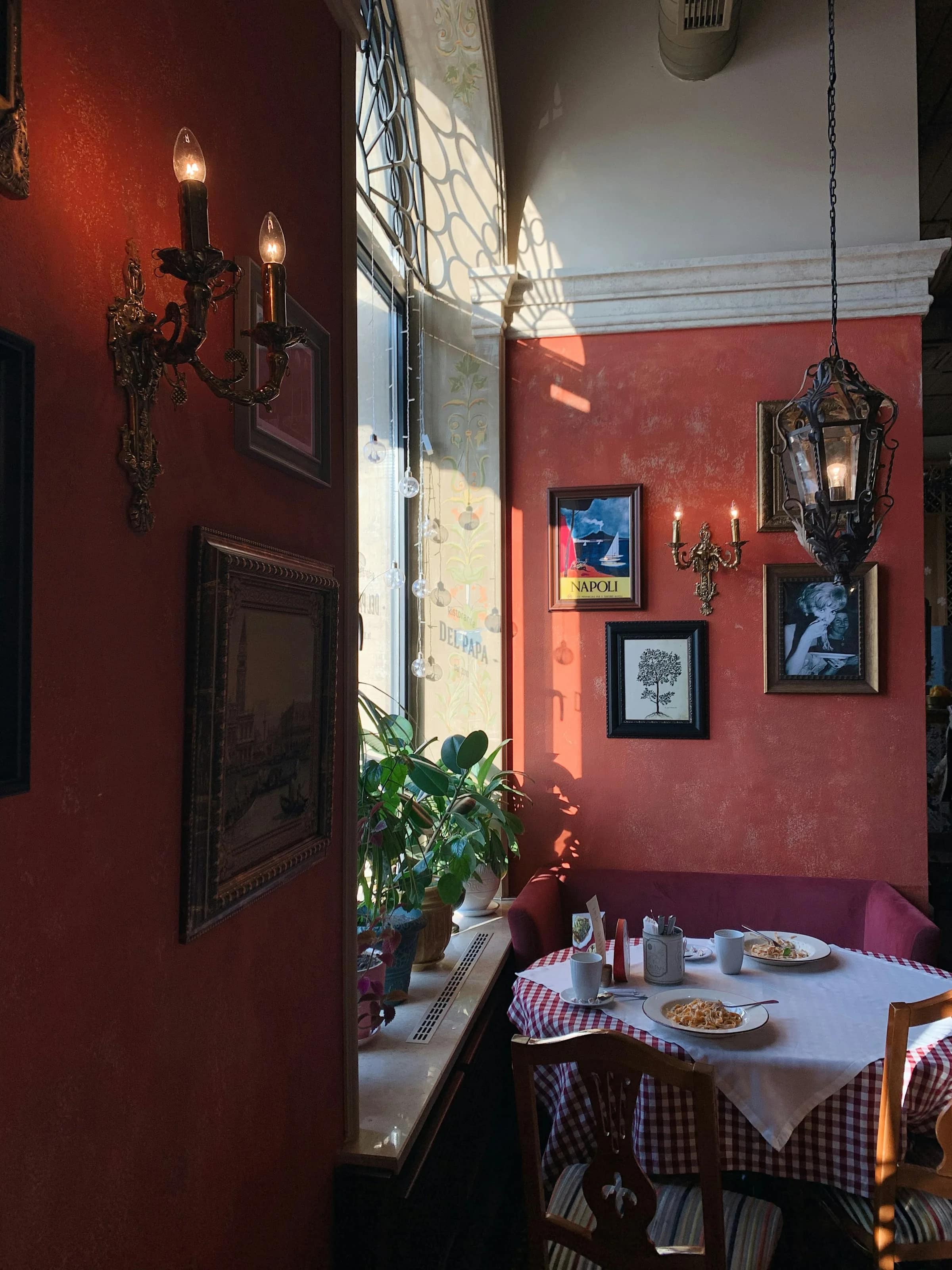 Sala da pranzo con le pareti rosse, i quadri appesi e le lanterne accese