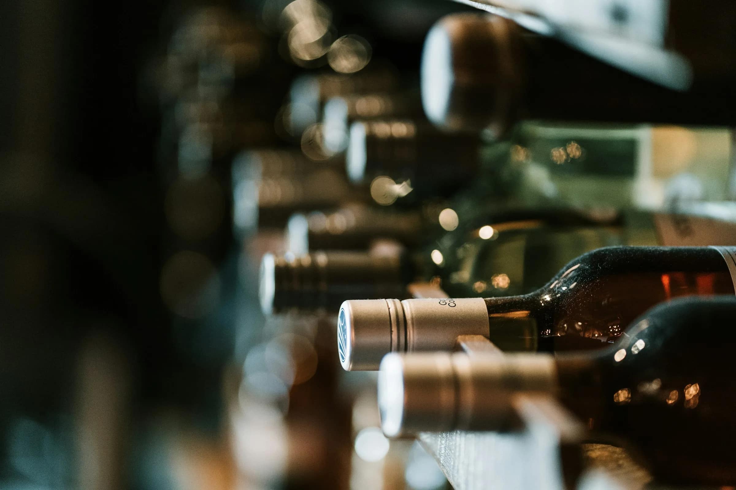 Bottiglie di vino coricate in cantina, illuminate di taglio